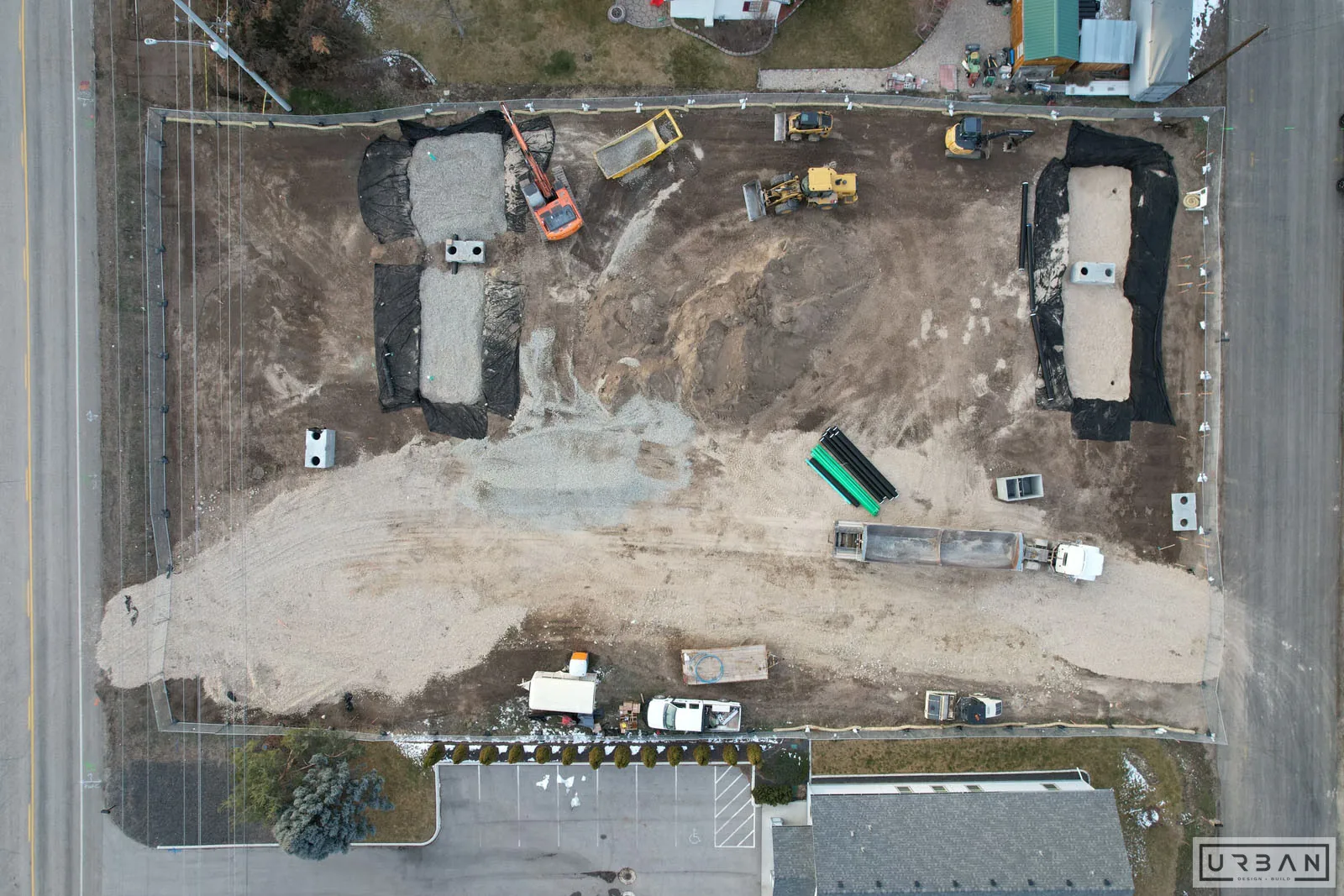 A graded development site with utilities being installed, seen from above