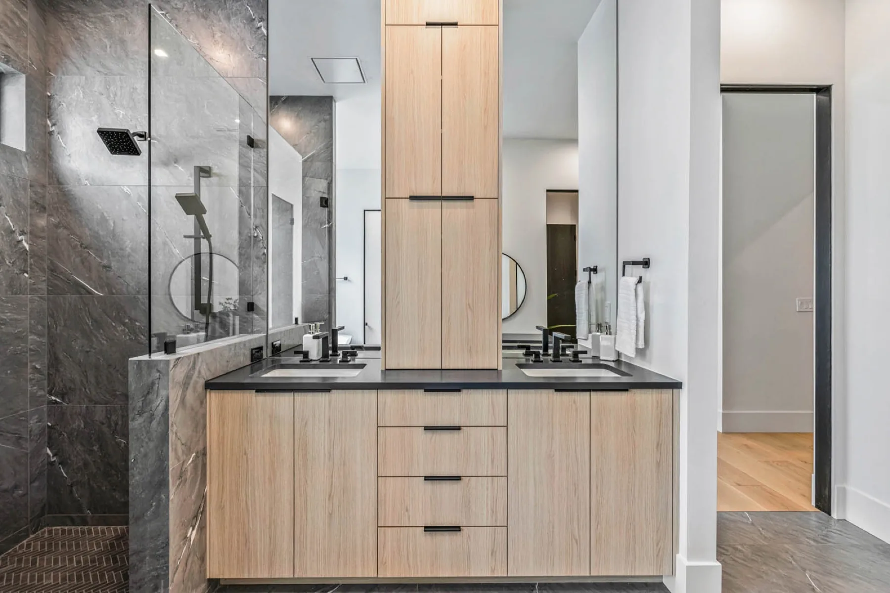 A finished primary bathroom with stone and white oak